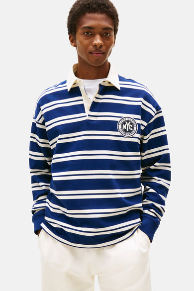 Sweater bleu de TOMMY HILFIGER avec des rayures blanches, porté avec un short blanc et des chaussures marron, dos.