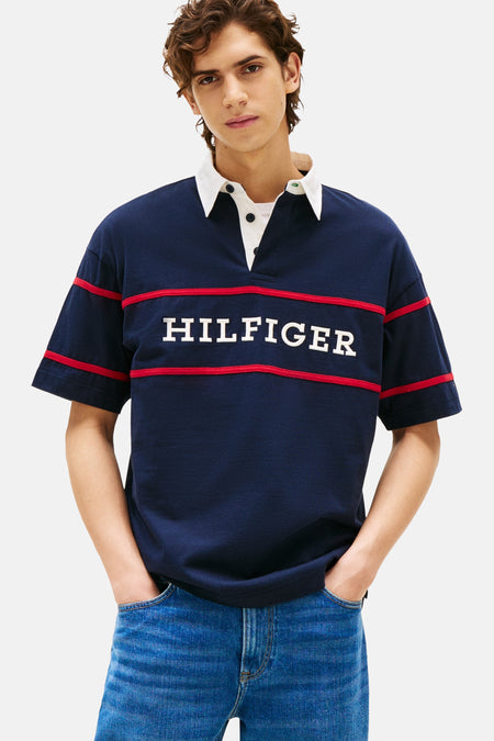 Polo bleu à manches courtes de Tommy Hilfiger, avec col blanc et rayures rouges avec nom de marque sur la poitrine.