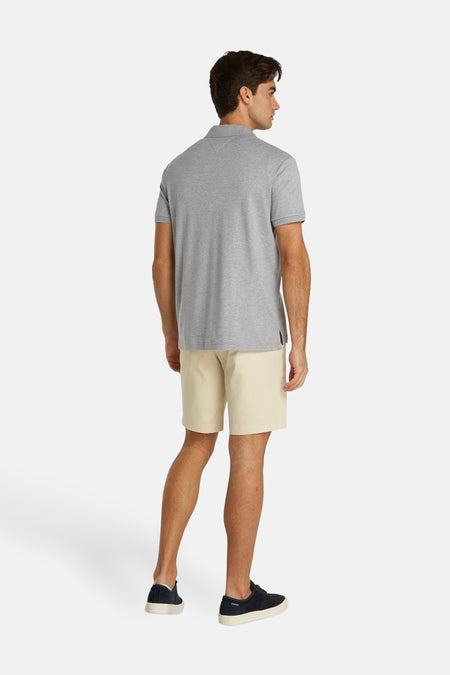 Polo gris de TOMMY HILFIGER, vue arrière, à manches courtes et texture mélangée, portée avec un short crème et des baskets foncées.