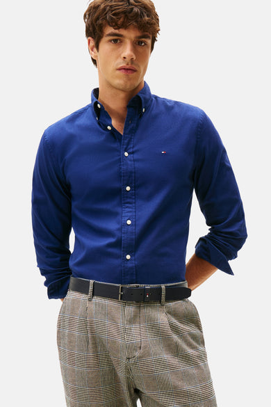 Chemise bleue à manches longues de Tommy Hilfiger, vue de derrière, avec un pantalon rayé et des chaussures noires.