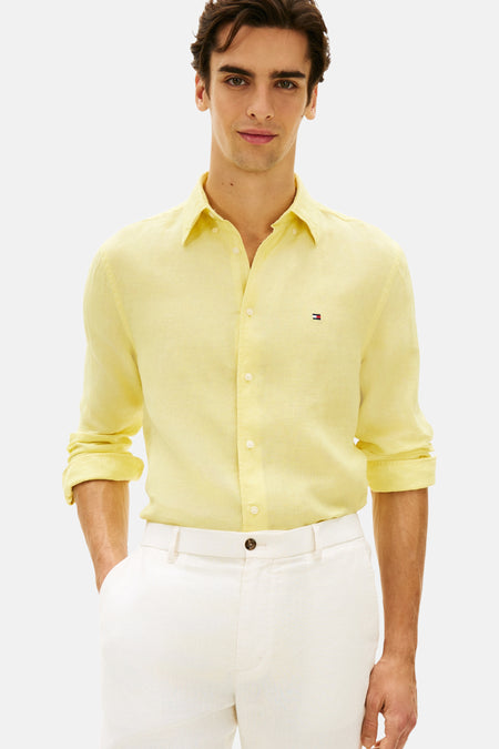 Chemise en lin jaune Tommy Hilfiger, à manches longues et coupe regular, portée avec un pantalon blanc et des chaussures noires.