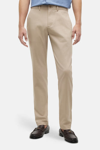 Chino beige de TOMMY HILFIGER, porté par un homme avec une chemise bleue, une ceinture marron et des mocassins foncés.