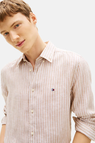 Chemise beige rayée à manches longues Tommy Hilfiger, avec fermeture boutonnée et logo sur la poitrine.
