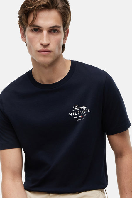 Donkerblauw T-shirt van TOMMY HILFIGER met logo op de borst, gedragen door een man met een beige broek.