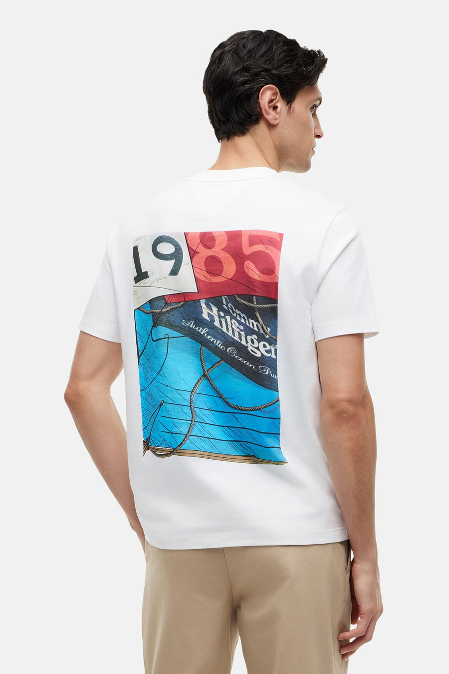 Witte korte mouw T-shirt van TOMMY HILFIGER met kleurrijke 1985 print op rug, zijaanzicht model
