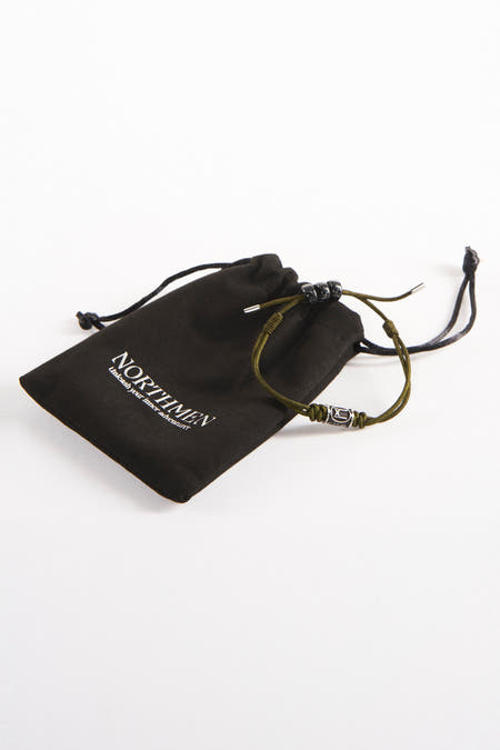 Bracelet brun de NORTHMEN, avec une chaîne coulissante décorative argentée, à côté d'un sac de rangement en tissu noir avec cordon.