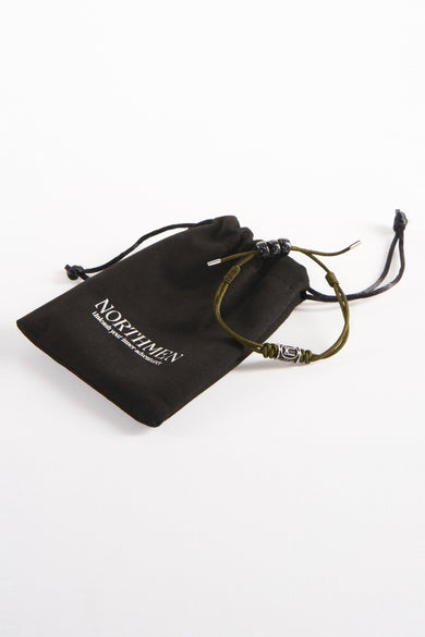 Bracelet brun de NORTHMEN, avec une chaîne coulissante décorative argentée, à côté d'un sac de rangement en tissu noir avec cordon.
