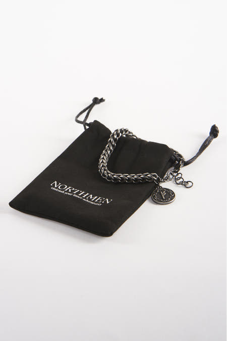 Bandeau noir de NORTHMEN, avec une chaîne argentée et un poussoir runique, reposant sur un sac en tissu noir.