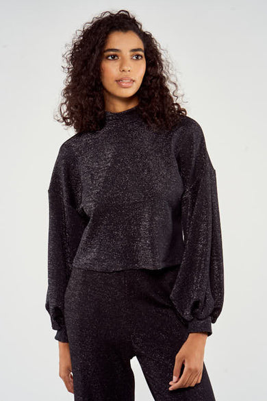 Pull noir avec col rond de NOOR BY NORA GHARIB, avec des manches ballon et une texture brillante.