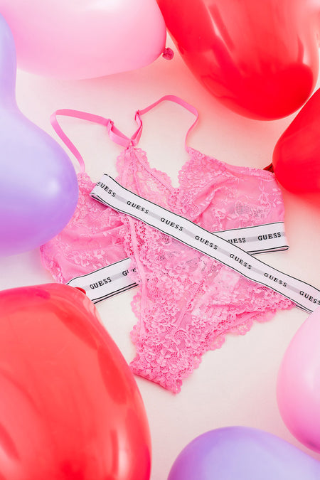 Robe rose de Guess, avec des détails sur les bords et entourée de ballons rouges et violets.