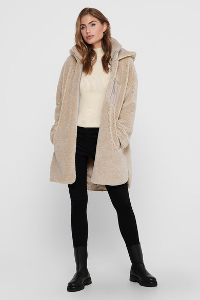 Doudoune longue beige d'ONLY, avec capuchon, combinée avec un legging noir et des bottes noires.