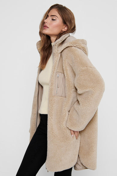Blouson long beige d'ONLY, avec capuchon et pantalon noir.