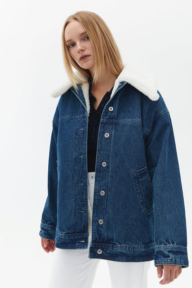 Jean en denim de OXXO, avec une col ted teddy blanc, visible sur le dos.