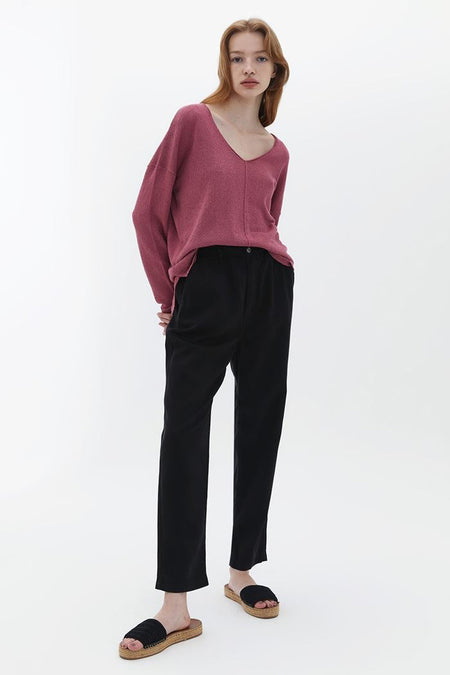 Pantalon noir d'OXXO, porté avec un gilet rose et des sandales à semelles en corde.
