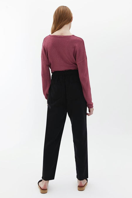 Pantalon noir OXXO, vu de l'rièrerière combiné avec une uneise rose et des sandales.