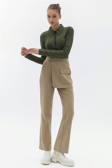 Pantalon beige d'OXXO, avec une poche décorative et une fermeture éclair à l'avant, associé à des bottes blanches.