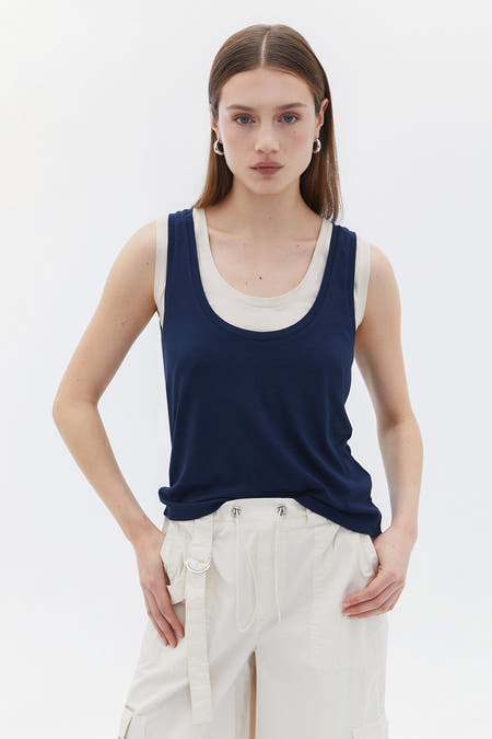 T-shirt bleu d'OXXO porté avec un haut de couleur crème et un pantalon cargo.