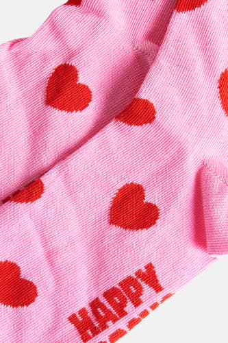 Chaussettes roses de Happy Socks®, avec des cœurs rouges et le mot "HAPPY" brodé dessus.