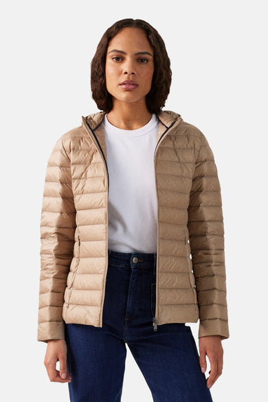 Manteaux de pluie beige de JOTT, avec capuche, portés sur une chemise blanche et un pantalon en cuir noir.