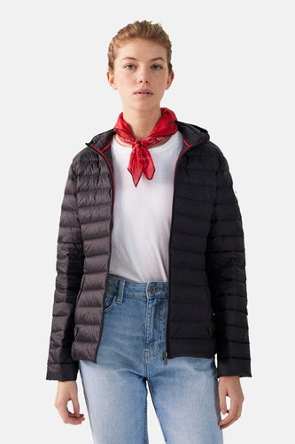 Vrouw draagt zwarte donsjas, wit T-shirt en blauwe jeans met een rode bandana om de nek.