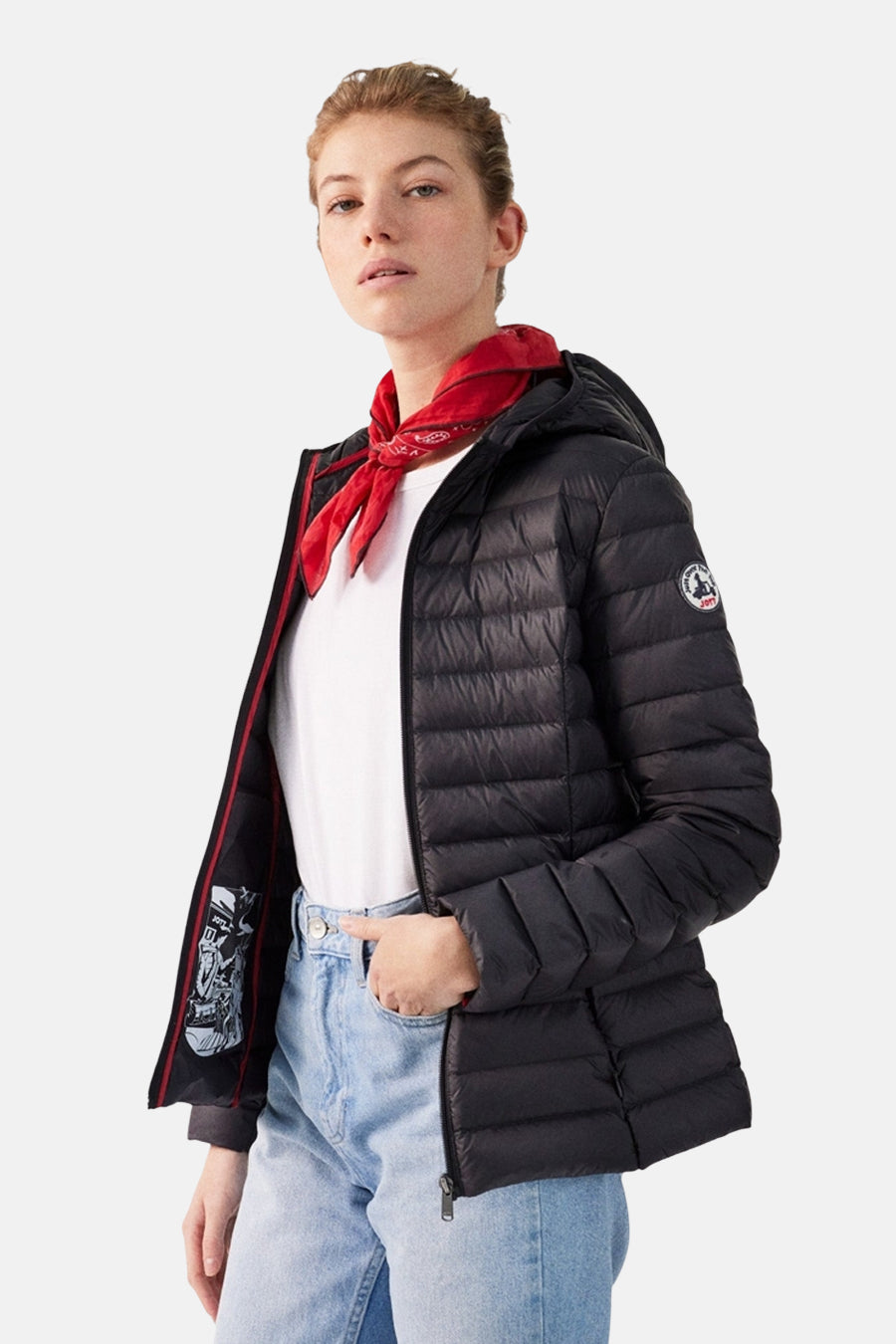 Vrouw in zwarte donsjas met rode bandana en blauwe jeans.