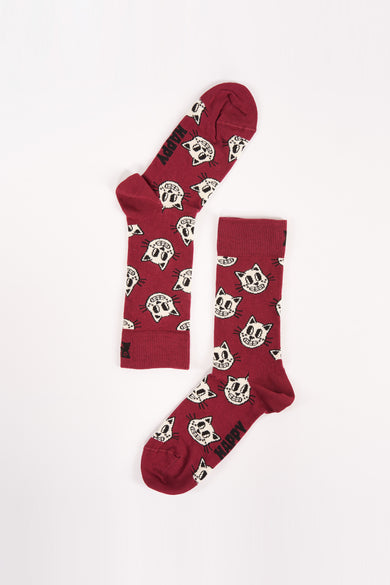 Chaussettes rouge foncé avec imprimé de petits chats blancs de Happy Socks, bord rayé et texte "HAPPY" sur les orteils, posées à plat sur fond blanc