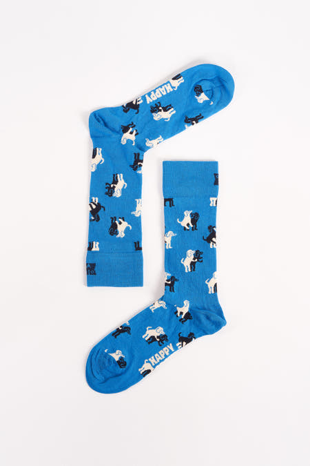 Chaussettes bleues avec imprimé de petits chiens noir et blanc de Happy Socks®, posées à plat sur fond blanc