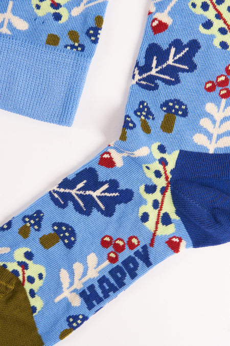 Chaussettes bleues à motif forestier de Happy Socks, avec des champignons, des baies et des plantes vertes, vue en gros plan