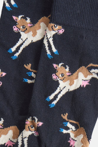 Chaussettes bleues de Happy Socks avec un motif de vaches courantes en brun, blanc et rose.