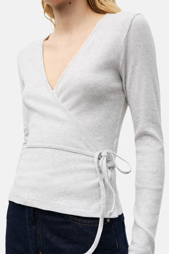 T-shirt gris à manches longues d'ENVII, avec détail de nouage et jeans foncés.
