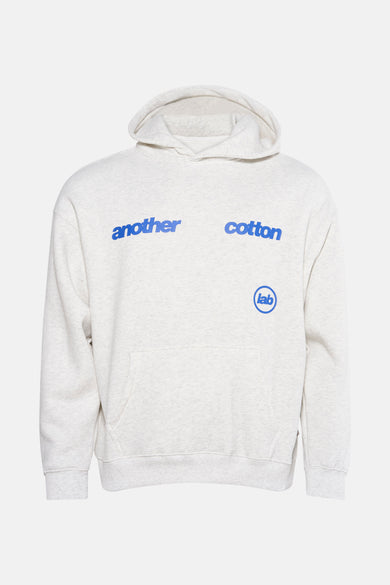 Pull-over gris avec capuche d'ANOTHER COTTON LAB, avec du texte bleu sur la poitrine et une poche à l'avant.