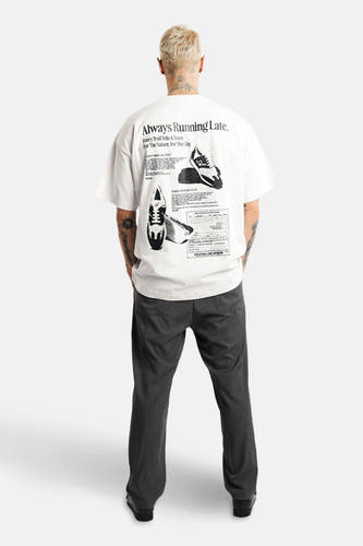 T-shirt blanc à manches courtes d'ANOTHER COTTON LAB, avec une impression noire sur le dos, associé à un pantalon gris.