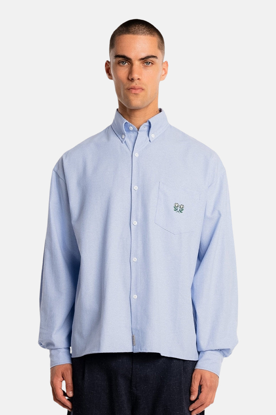 Chemise bleue à manches longues d'Another Cotton Lab, avec des fleurs brodées sur la poche poitrine.