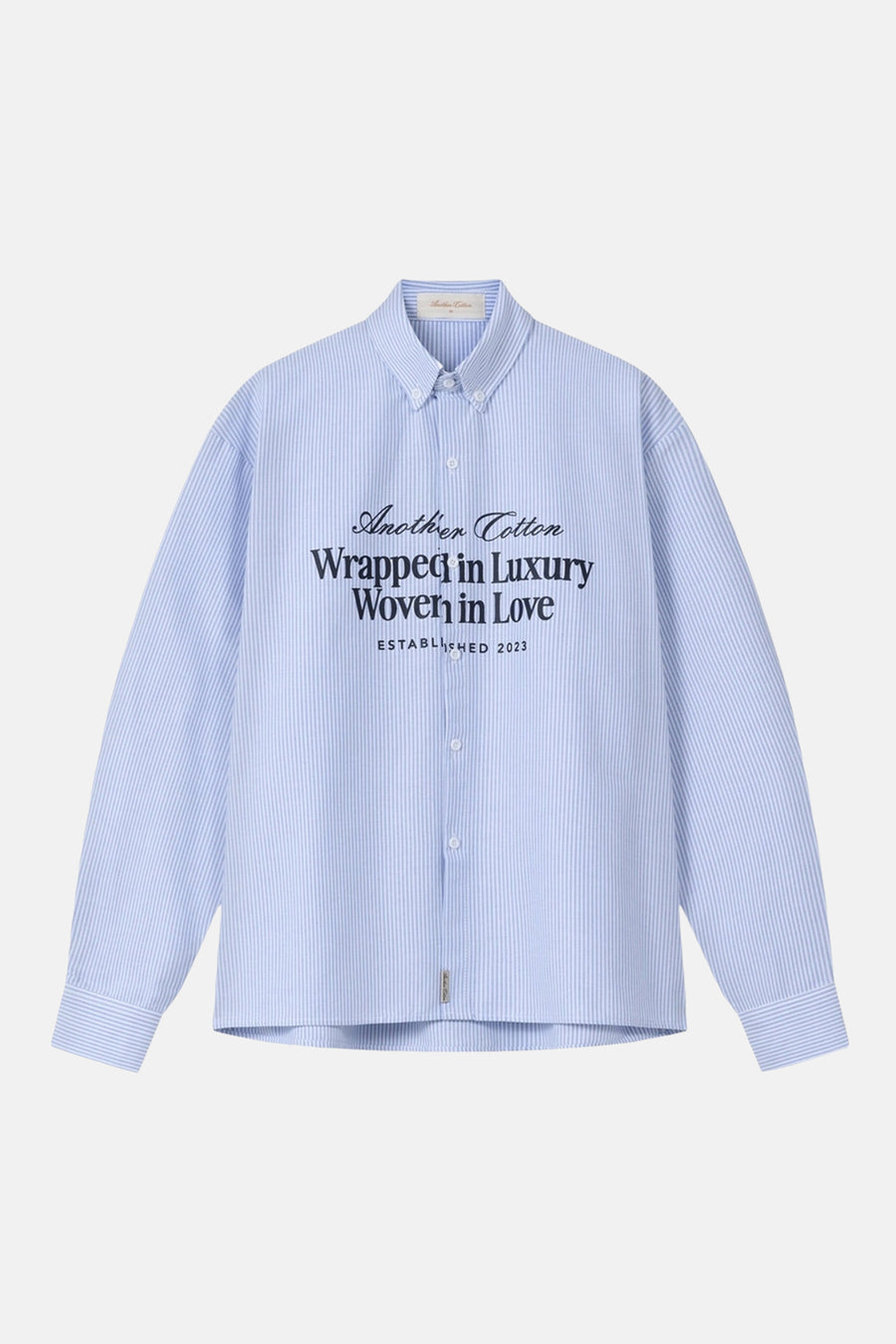 Chemise bleue à rayures à manches longues d'Another Cotton Lab, avec un imprimé texte sur le devant.