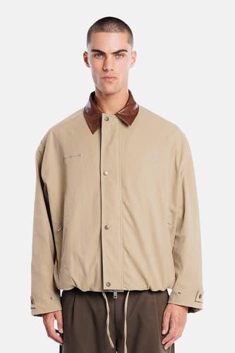 Manteau court beige de ANOTHER COTTON LAB, avec col marron et écusson dans le dos.
