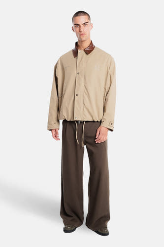 Manteau court beige de ANOTHER COTTON LAB, avec col marron et pantalon drapé marron.