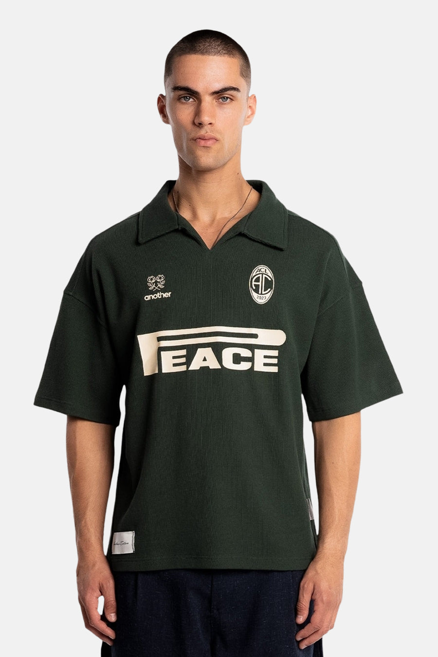 Polo verte à manches courtes de couleur verte de ANOTHER COTTON LAB, avec imprimé "PEACE" et logos sur la poitrine.