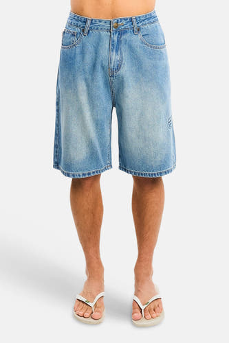 Lichtblauwe denim jeansshorts van ANOTHER COTTON LAB, front view, met vervaagde was, zakken en klein logo op been, gedragen met witte slippers.