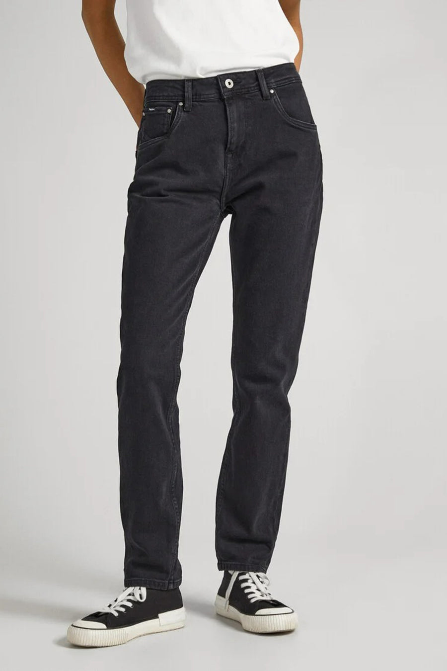 Plan rapproché d'une personne portant des jeans noirs, debout.