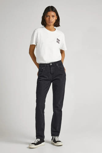 Femme en t-shirt blanc, jeans noirs et baskets sur fond blanc.