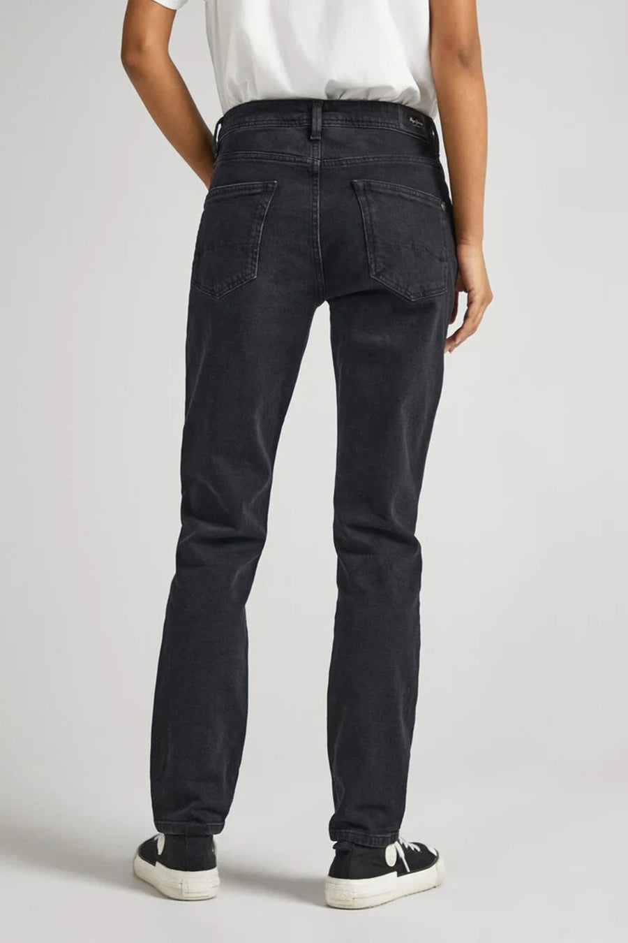 Dos d'un personne en en jeans noir et et et contre un fond fond blanc.