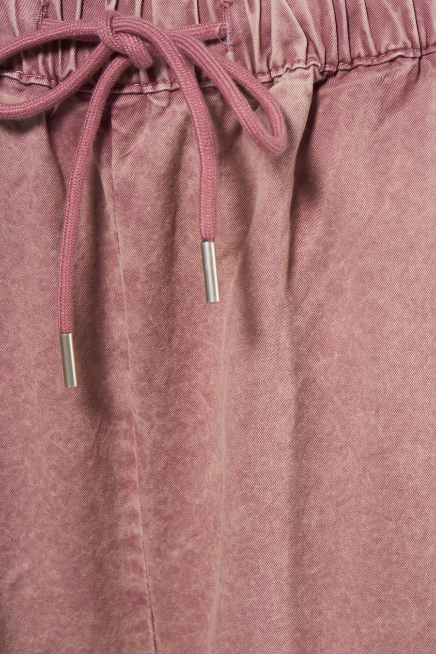Pantalon rose ADORE, avec une ceinture élastique et un cordon de serrage rose avec embouts métalliques.