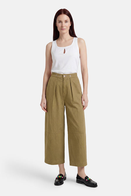 Groene chino broek van ADORE met hoge taille en wijde pijpen, gedragen met wit tanktop en zwarte loafers, front view