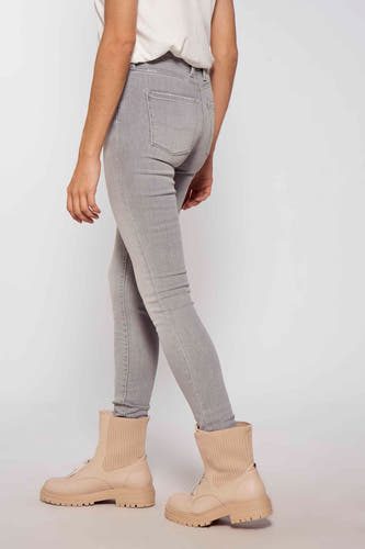 Jean skinny gris de Pepe Jeans, porté avec des bottes crème à grosses semelles, vu de côté.