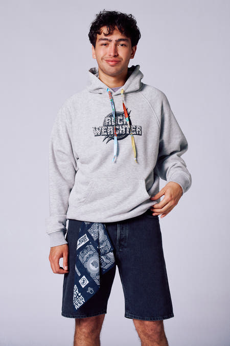 Pull-over gris avec capuche de Rock Werchter 50, avec logo sur la poitrine et bandana bleu dans le pantalon.