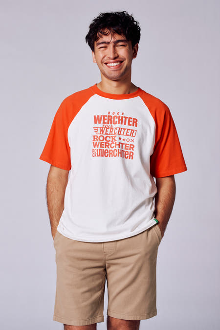 T-shirt blanc avec des manches oranges courtes de Rock Werchter 50, imprimé et porté avec des shorties beige.