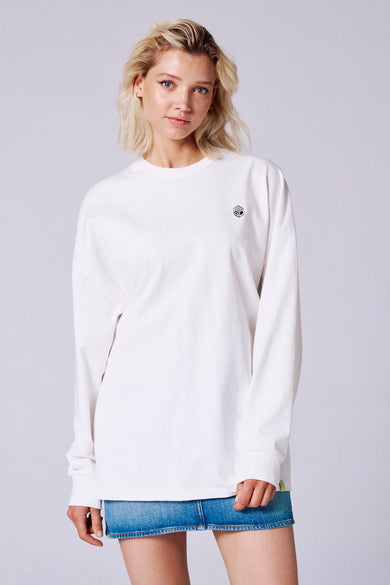 T-shirt blanc à manches longues de Rock Werchter 50, avec un petit logo et porté avec une veste en cuir.