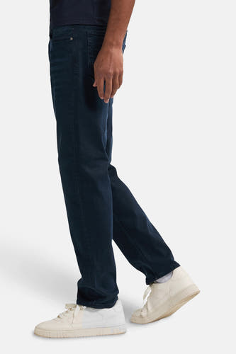 Jean tapered bleu de Petrol Industries, avec des baskets blanches et un t-shirt bleu marine.