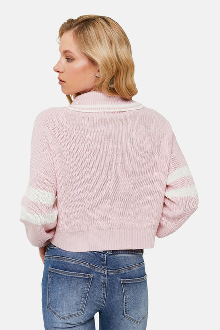 Roze gebreide sweater met blauwe jeans.