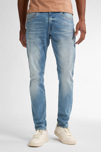 Jean slim de Petrol Industries, avec un léger lavage et des baskets beige.